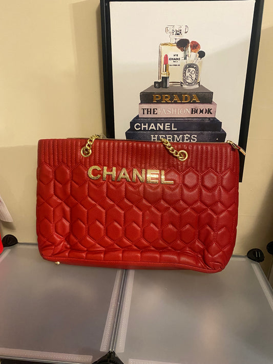 Red Chanel bag with gold Chanel logo front of the bag